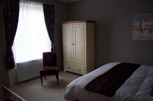 a bedroom with a bed and a cabinet and a chair at The Clyffe Hotel in Lowestoft