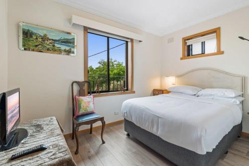 a bedroom with a bed and a desk with a television at Spacious 2-Bed Apartment Minutes From Elwood Beach in Melbourne