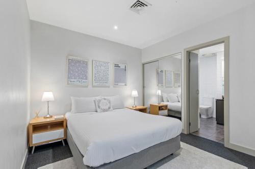 a white bedroom with a bed and a bathroom at Sophisticated CBD 2-Bed Apartment by Yarra River in Melbourne