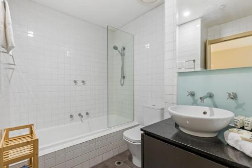 a white bathroom with a sink and a shower at Sophisticated CBD 2-Bed Apartment by Yarra River in Melbourne
