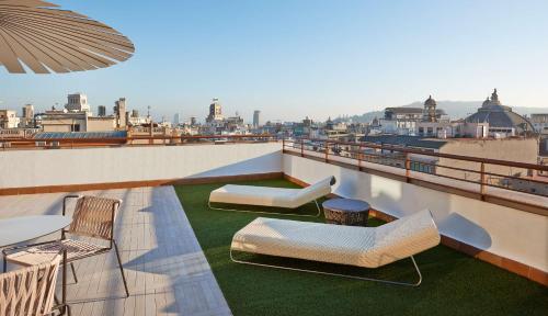 a balcony with chairs and tables on a roof at NH Collection Barcelona Gran Hotel Calderon in Barcelona