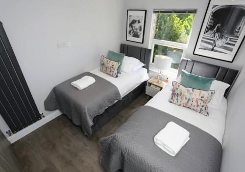 フィンチリーにあるAisiki Apartments at Stanhope Road, North Finchley, a Multiple 2 or 3 Bedroom Pet-Friendly Duplex Flats, King or Twin Beds with Aircon & FREE WIFIのベッド2台と窓が備わる小さな客室です。