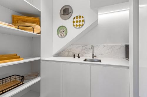 een keuken met witte kasten en een wastafel bij Impeccably Chic 3-Bed House by Fawkner Park in Melbourne