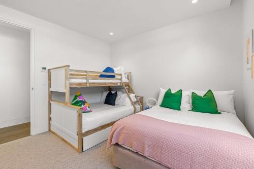 een slaapkamer met een stapelbed en groene kussens bij Impeccably Chic 3-Bed House by Fawkner Park in Melbourne