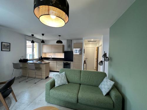 un salon avec un canapé vert et une cuisine dans l'établissement CANIGOU, à Port-Vendres