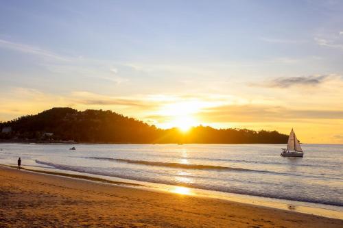 a sail boat on the beach at sunset at Arinara Beach Resort Phuket - SHA Extra Plus in Bang Tao Beach
