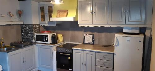 a kitchen with white cabinets and a white refrigerator at Maison des Gabelous in Guipry-Messac