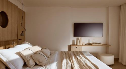 a bedroom with a white bed with a tv on the wall at St. Nicolas Bay Resort Hotel & Villas in Agios Nikolaos