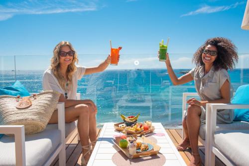 twee vrouwen die op stoelen cocktails drinken op een balkon bij One Ibiza Suites in Ibiza-stad