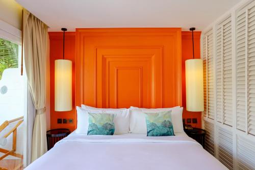 a bedroom with a white bed with an orange headboard at Arinara Beach Resort Phuket - SHA Extra Plus in Bang Tao Beach