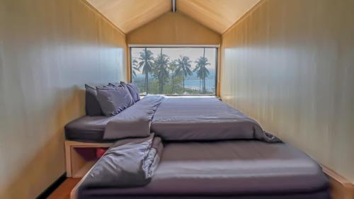 Bobocabin Bunaken Hills, Manado في مانادو: سريرين في غرفة صغيرة مع نافذة