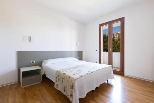 ポルト・チェザーレオにあるAppartamento del Tramonto by Le Dune Villasの白いベッドルーム(ベッド1台、大きな窓付)