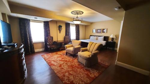 a hotel room with a bed and a couch and chairs at Grant Hall Hotel in Moose Jaw