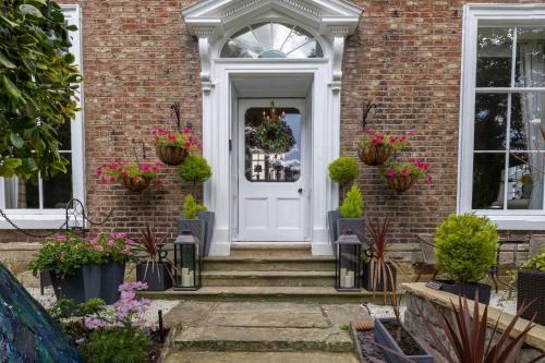 a white front door of a brick house with potted plants at Highgate House in Whitby