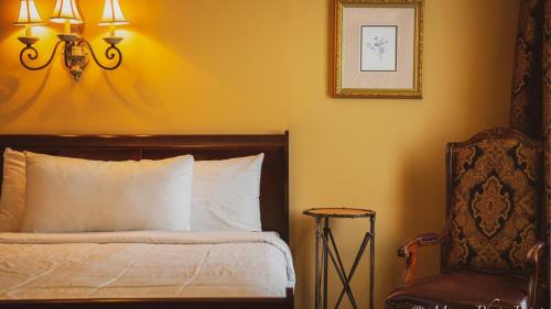 a bedroom with a bed and a chair and a picture at Grant Hall Hotel in Moose Jaw