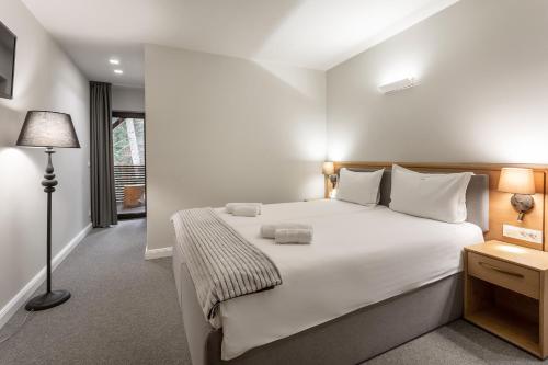 a bedroom with a large white bed and a lamp at Eden 1 & Eden 2 in Predeal