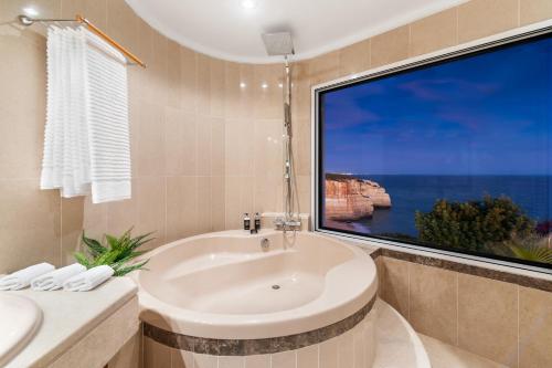 a bathroom with a tub and a large window at Seafront View next to the famous “Benagil Caves” in Benagil