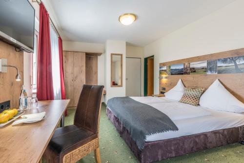 ein Hotelzimmer mit einem Bett, einem Tisch und einem Schreibtisch in der Unterkunft Rührberger Hof Hotel & Restaurant Grenzach-Wyhlen bei Basel in Grenzach-Wyhlen