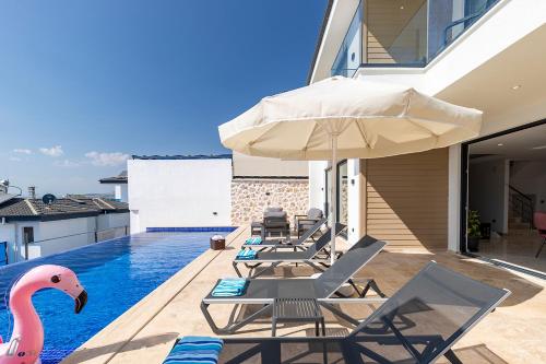 a swimming pool with lounge chairs and an umbrella at Tashan Villas in Kas