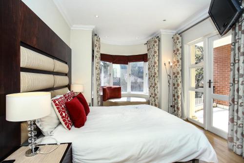 een slaapkamer met een groot wit bed met rode kussens bij The Melrose Kernick Avenue Apartment in Johannesburg