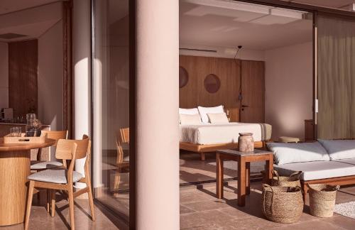 a bedroom with a bed and a table and chairs at St. Nicolas Bay Resort Hotel & Villas in Agios Nikolaos