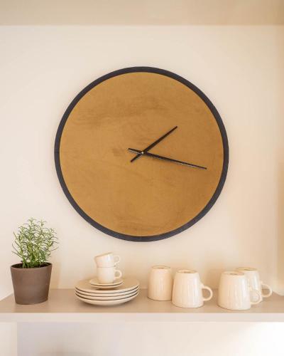 a clock on a wall above a shelf with dishes at Domizil am Gohrisch in Kurort Gohrisch