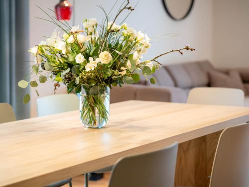 a vase of white flowers sitting on a wooden table at Domizil am Gohrisch in Kurort Gohrisch
