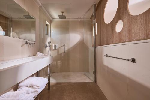 a bathroom with a glass shower and a sink at St. Nicolas Bay Resort Hotel & Villas in Agios Nikolaos