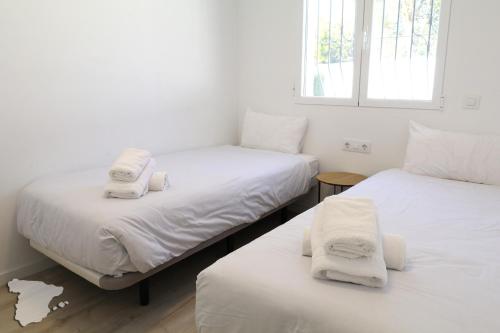 2 Betten in einem Zimmer mit weißer Bettwäsche und Handtüchern in der Unterkunft Casita Adelfa in Calpe