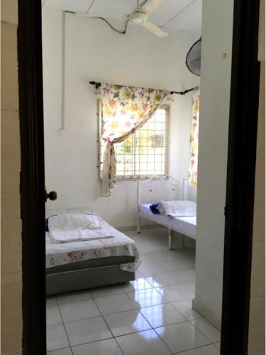 a bedroom with two beds and a window at Addeen homestay in Kemaman