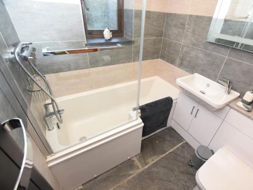ein Badezimmer mit einer weißen Badewanne und einem Waschbecken in der Unterkunft 3 Bed in Padstow 51214 in Padstow