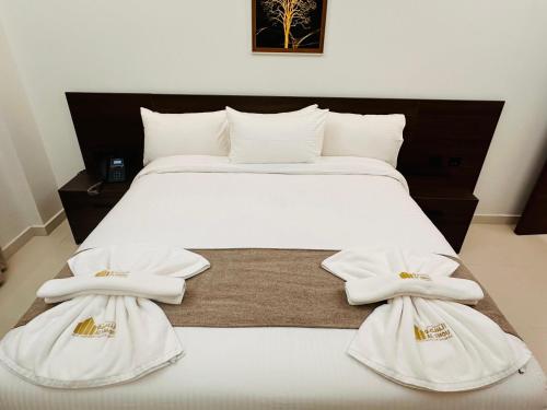 السمو ALSMOU للشقق الفندقية في نزوى‎: غرفة نوم عليها سرير وفوط بيضاء