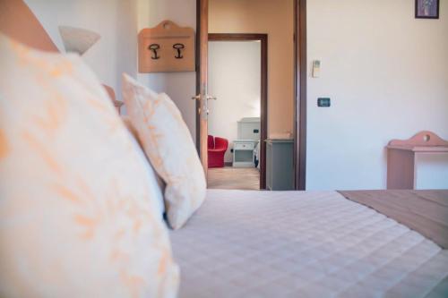 a bedroom with a bed with white sheets and pillows at Hotel Cardedu in Cardedu