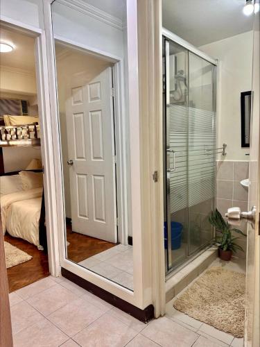 a bathroom with a shower and a glass door at East Ortigas Mansions by MA in Manila