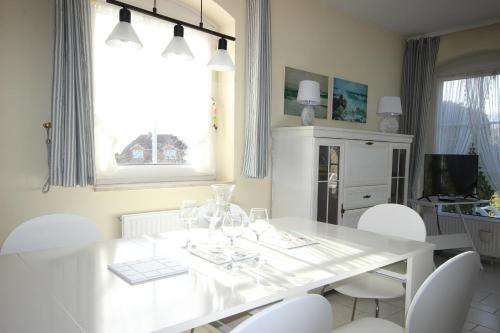 une salle à manger blanche avec une table et des chaises blanches dans l'établissement Haus am Fuchskamp, à Grömitz