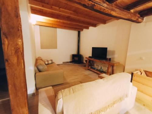 ein Wohnzimmer mit einem Sofa und einem TV in der Unterkunft La Cabaña del Risco in Ligos