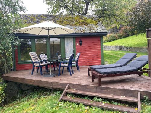 a deck with a table and chairs and an umbrella at Kvammen in Sæbø