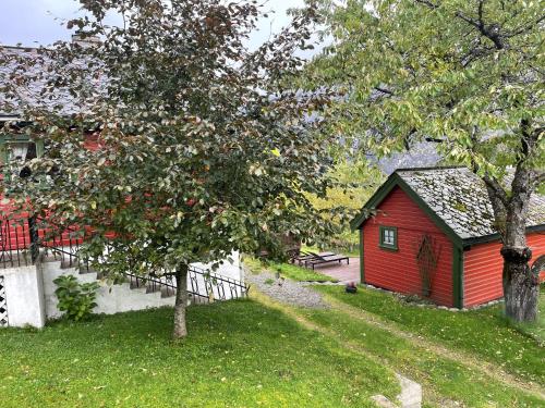 a red house in a yard with a tree at Kvammen in Sæbø