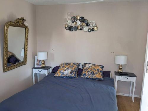 1 dormitorio con 1 cama azul, 2 mesas y espejo en Maison familiale spacieuse proche Aix/Marseille en Vitrolles
