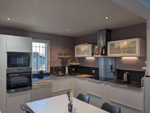 une cuisine avec des armoires blanches et une table à l'intérieur dans l'établissement Maison familiale spacieuse proche Aix/Marseille, à Vitrolles