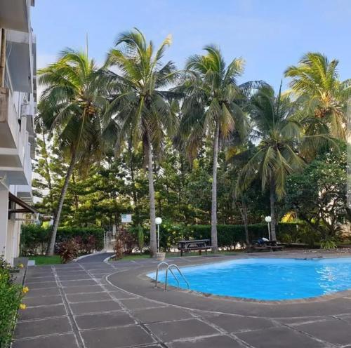 a swimming pool with palm trees in the background at Le Residence Blue Bay in Blue Bay