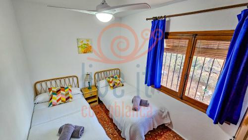 - une chambre avec 2 lits et une fenêtre avec des rideaux bleus dans l'établissement CASA MANZANO. MORAIRA. LIVE IT COSTABLANCA, à Moraira