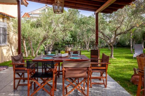 a dining table and chairs on a patio with trees at The Garden Villa Hanioti in Hanioti