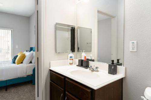 a bathroom with a sink and a mirror and a bed at Corporate Housing by MGM in Farmers Branch