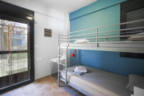 a room with a bunk bed with a blue wall at Pelagos Paradise Seafront Villa by Booking Kottas in Kalamitsi