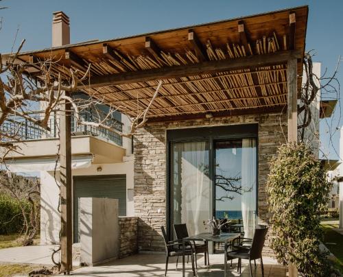 a patio with a table and chairs under a pergola at Pelagos Paradise Seafront Villa by Booking Kottas in Kalamitsi