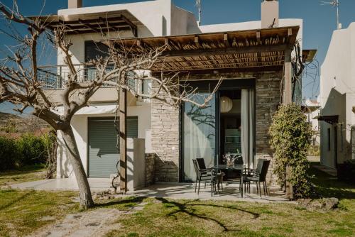 a patio with a table and chairs in front of a house at Pelagos Paradise Seafront Villa by Booking Kottas in Kalamitsi