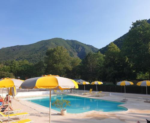una piscina con ombrelloni, sedie e montagne di Les Eaux Chaudes a Digne-Les-Bains
