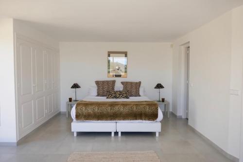 a white bedroom with a large bed and two lamps at Villa Dream - Santa Eulalia in Cala Llonga
