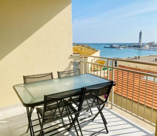 une table et des chaises sur un balcon avec vue sur l'eau dans l'établissement ''Le Phare''grand T3 vue imprenable sur le port et la mer !, à Sète